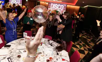 Corporate team enjoying Disco Bingo at a lively team building event with music, party games, and dancing at a hotel venue in Ireland