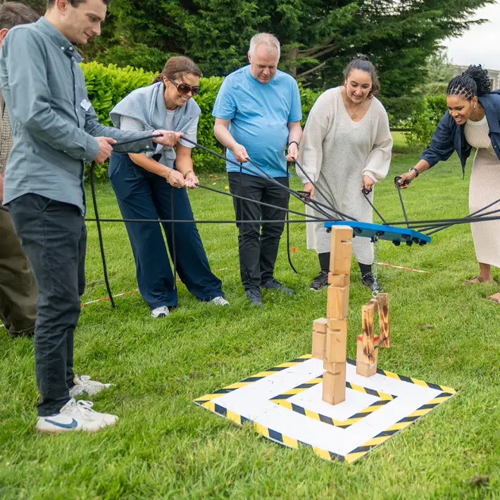 Corporate team using ropes to complete a collaborative block stacking challenge during The Challenger team building activity in Ireland