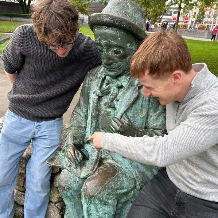 Two Fidelity Investments employees completing a photo challenge beside a bronze statue during their Galway team-building treasure hunt.
