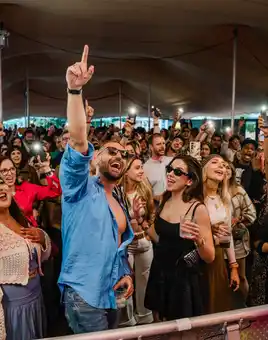 Corporate summer party with DJ playing to a crowd in front of a main stage decorated with lights and flags