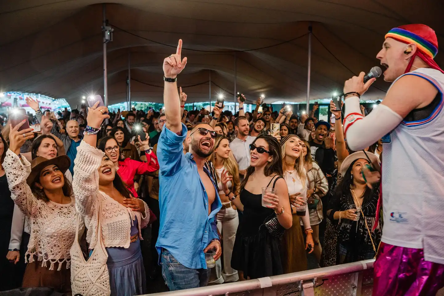 Corporate summer party with DJ playing to a crowd in front of a main stage decorated with lights and flags