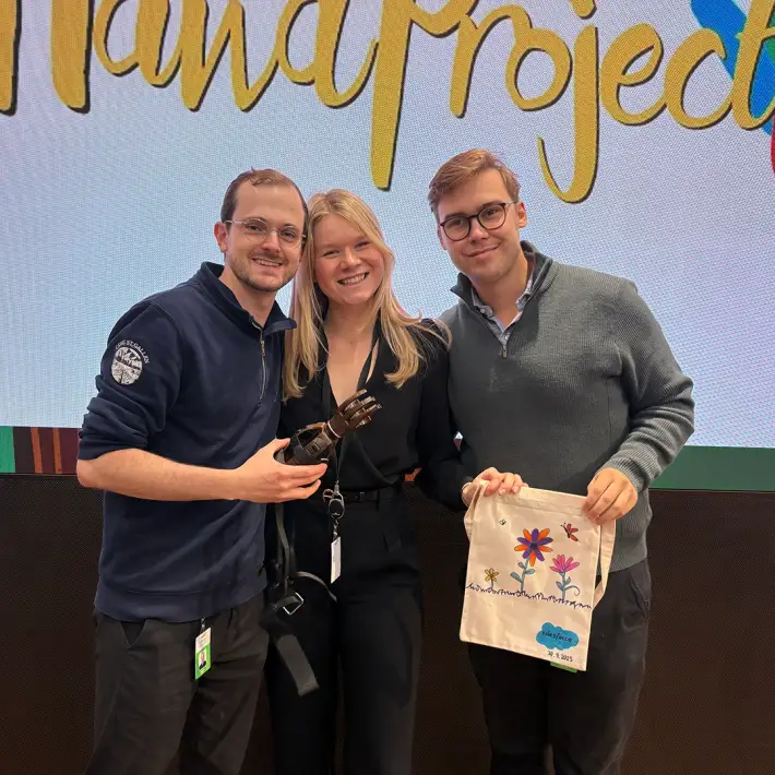 Colleagues holding a completed prosthetic hand and colourful donation bag after The Hand Project CSR team building activity in Ireland.