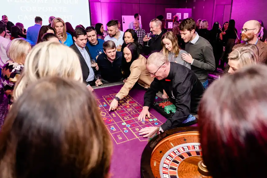 Corporate team activities Ireland casino night with staff gathered around roulette table