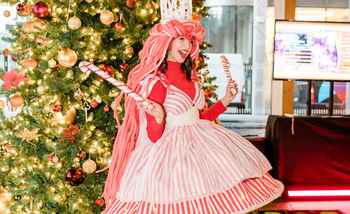 girl dressed up in Christmas outfit with a christmas tree behind her 