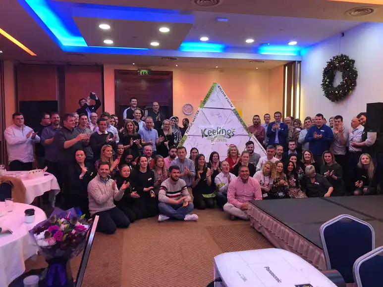 Large corporate team posing with their completed Pyramid Power structure during a creative team building event in Ireland.