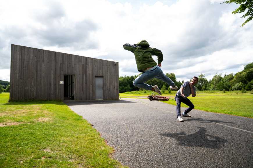 Two colleagues playfully posing and jumping outdoors during summer corporate team building activity