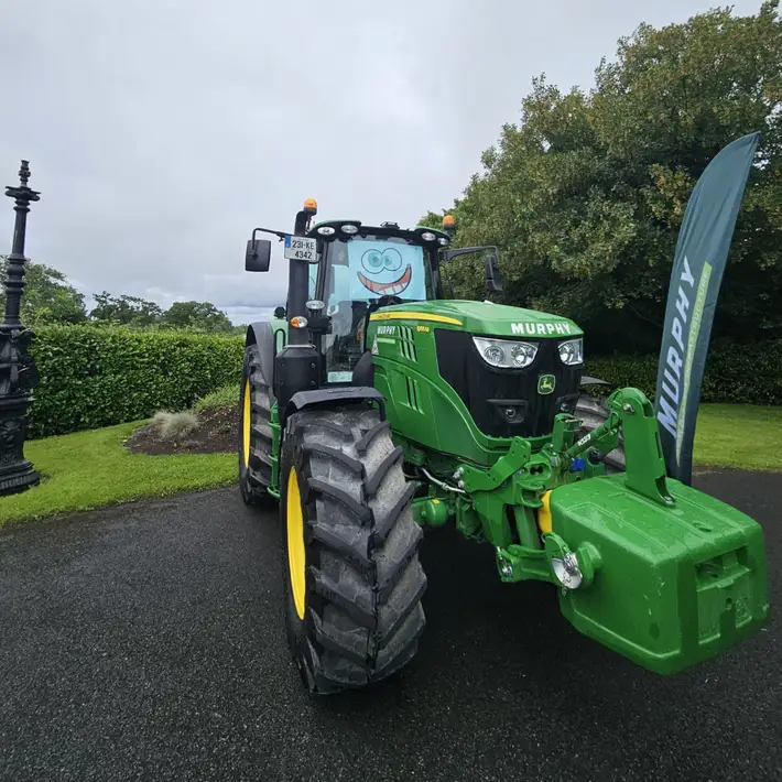 Green murphy group tractor with silly face at the front.