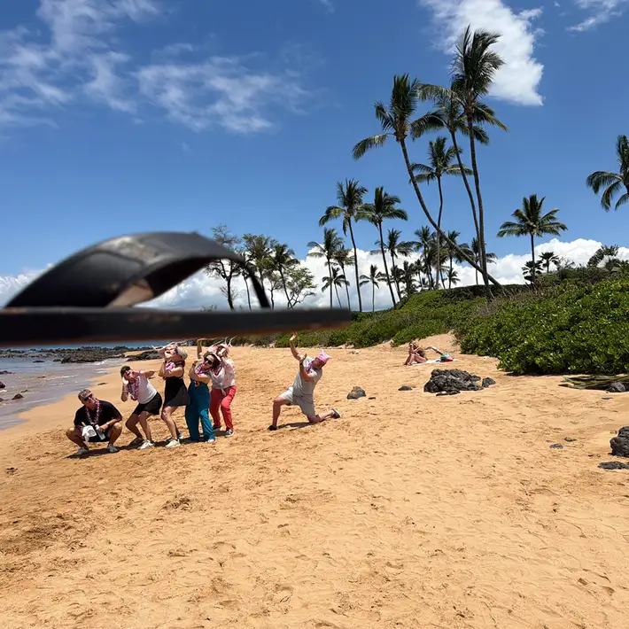 Team completing creative photo challenge on beach during corporate treasure hunt in Hawaii