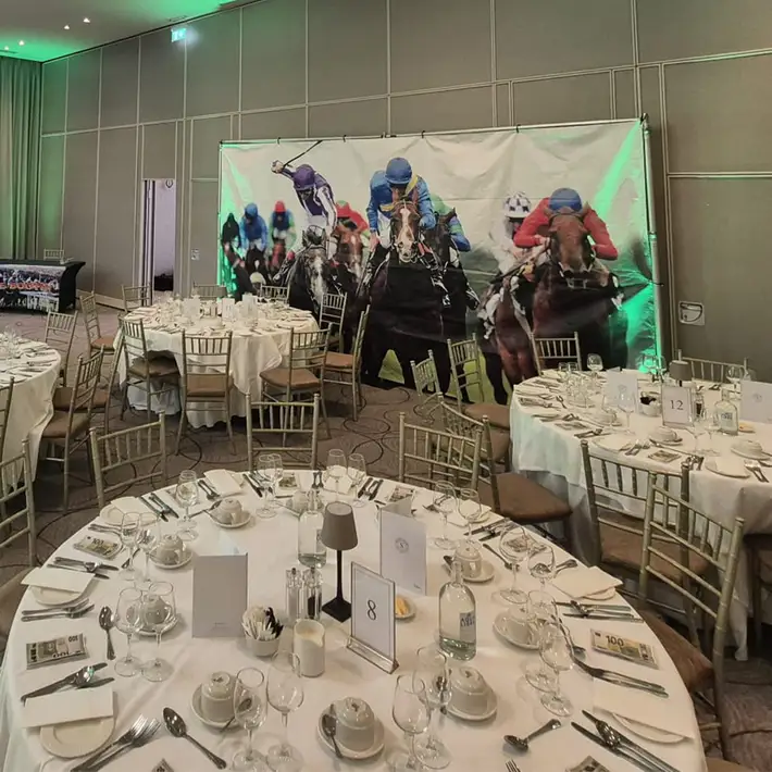 Corporate Race Night dinner setup with horse racing backdrop and themed event décor