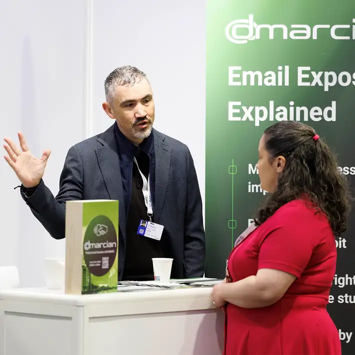 Dmarcian representative speaking with a visitor at the company's cybersecurity exhibition stand during the NCSC Cyber Expo in Dublin.