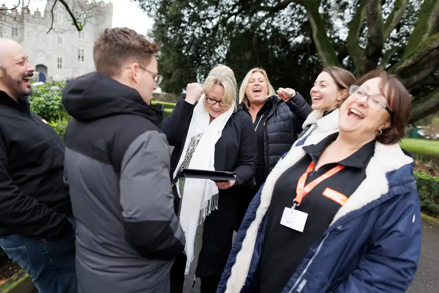 Group of colleagues laughing and celebrating a task completed in a digital team-building challenge