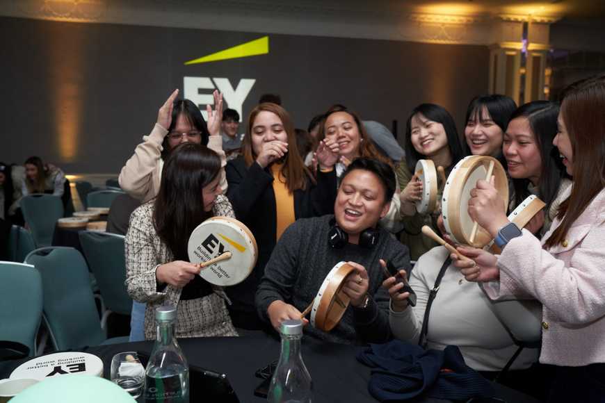 Close-up group of colleagues laughing and taking a team selfie using a tablet during an engaging workplace values event.