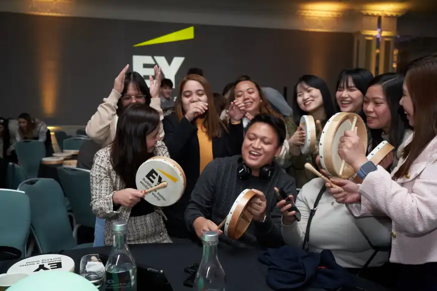 EY staff enjoying a Bodhrán drumming workshop during a fun corporate team building event in Ireland.