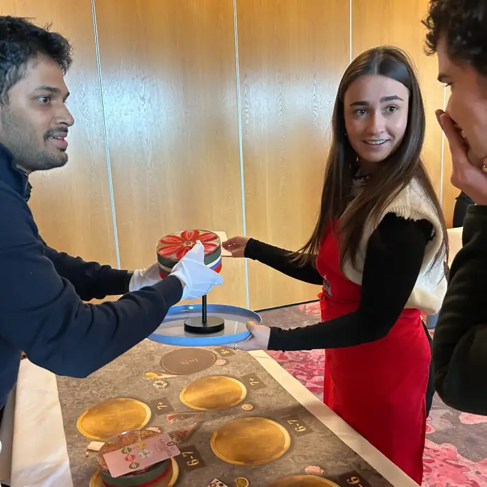 Corporate team training simulation in Ireland showing participants collaborating to deliver a completed cake under time pressure during The Cake Factory workshop