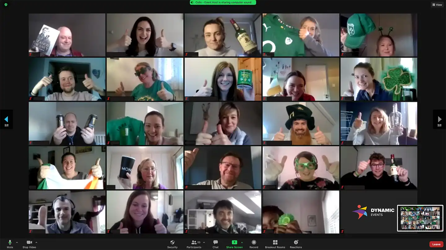 A vibrant virtual St. Patrick’s Day event featuring a multinational corporate team on a video call. Participants are dressed in festive green attire, holding Irish-themed props, and giving thumbs-up, creating an engaging and celebratory atmosphere. The Dynamic Events logo is visible, reinforcing the corporate virtual team-building theme.