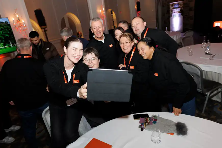 Female-led team huddled around a tablet collaborating on a task during a digital treasure hunt