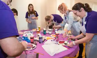 Corporate team painting activity in Ireland with colleagues collaborating and creating artwork together during a creative team building event.