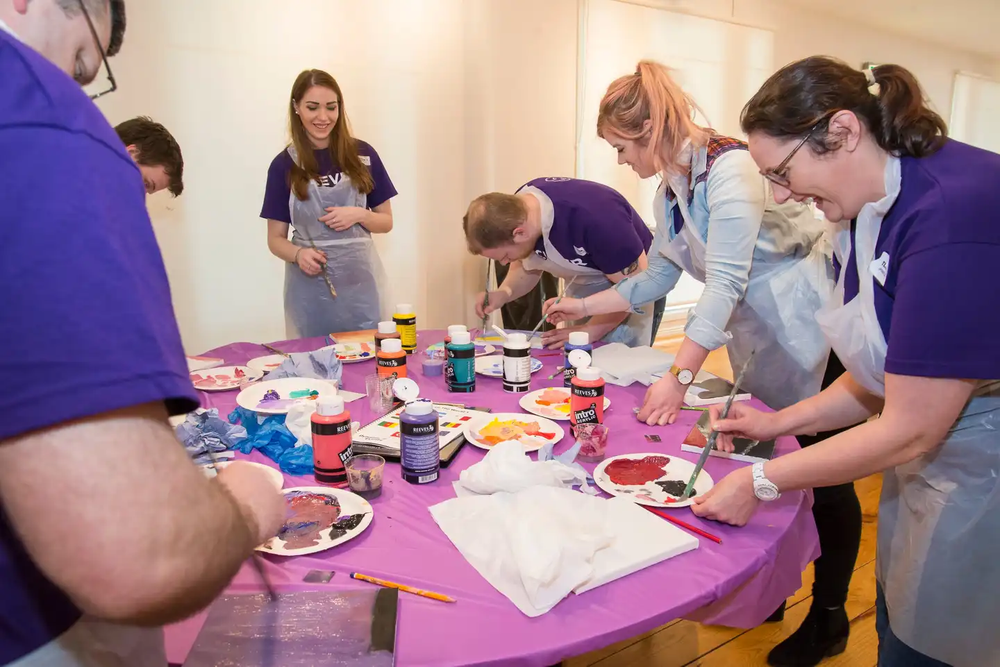 Corporate team painting activity in Ireland with colleagues collaborating and creating artwork together during a creative team building event.