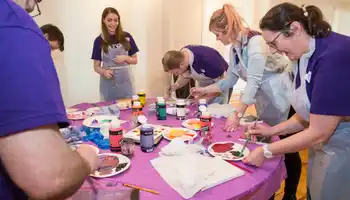 Corporate team painting activity in Ireland with colleagues collaborating and creating artwork together during a creative team building event.