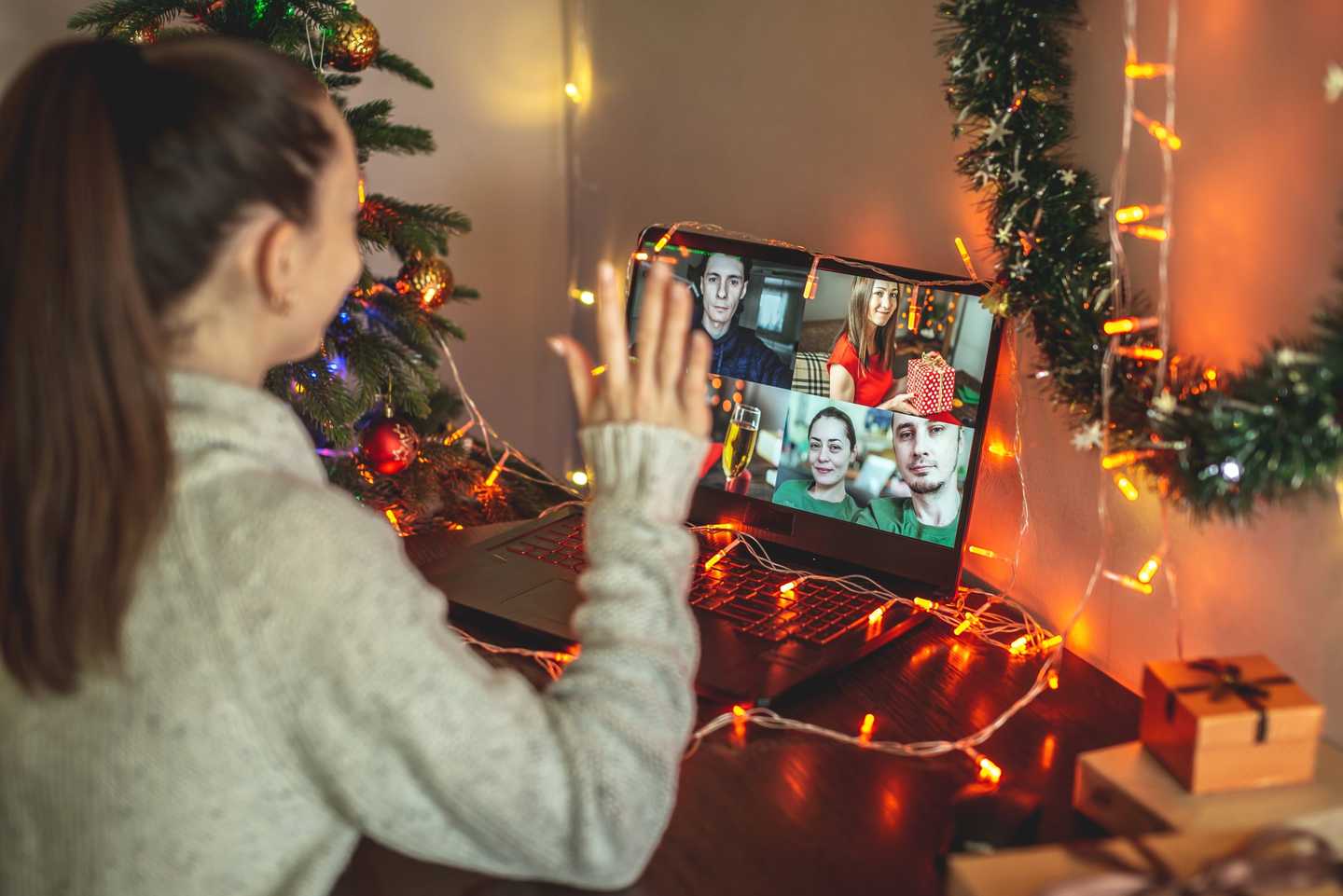 Remote employee taking part in a virtual Christmas event on a video call with festive decorations and team members on screen