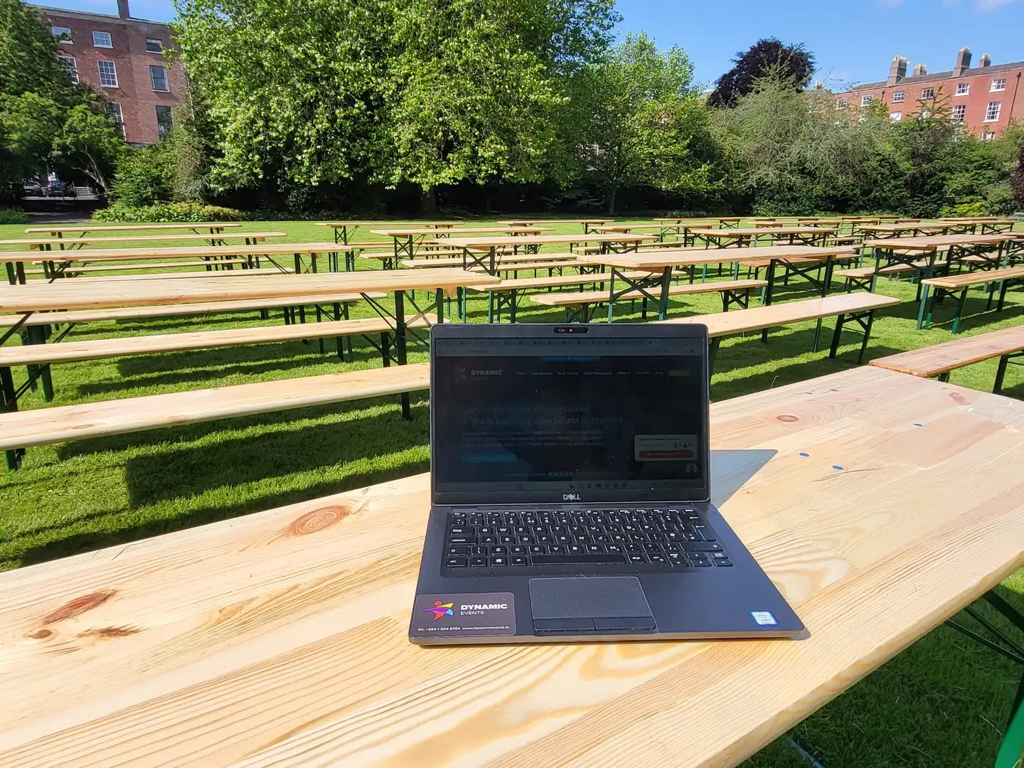 Picnic benches set up for a corporate hospitality event in a green park setting with surrounding Georgian buildings.
