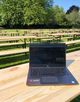 Picnic benches set up for a corporate hospitality event in a green park setting with surrounding Georgian buildings.
