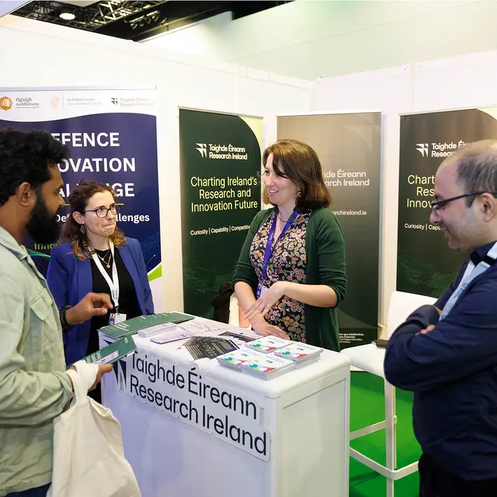 Research Ireland representatives speaking with visitors at their exhibition stand during the NCSC Cyber Expo in Dublin.
