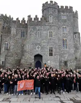 Corporate leadership team building event in Ireland with large group celebrating outside a historic castle venue