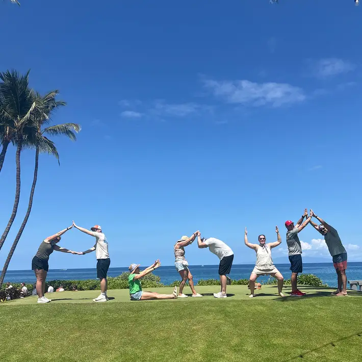 Teams completing group photo challenge on resort lawn during Hawaii team building event