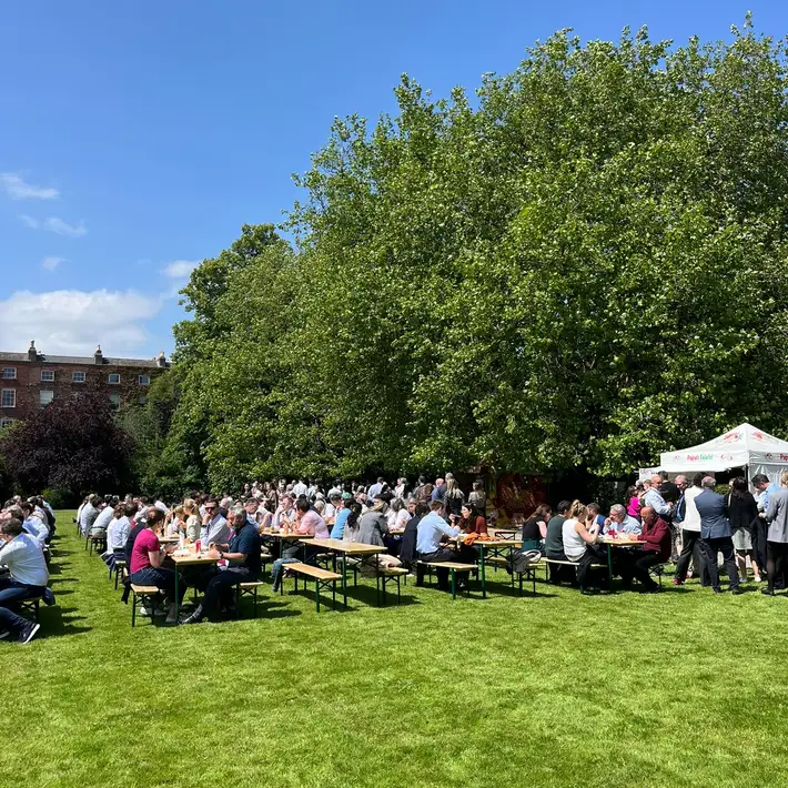 SMBC team members seated on picnic benches enjoying an outdoor corporate lunch in Fitzwilliam Square, Dublin.