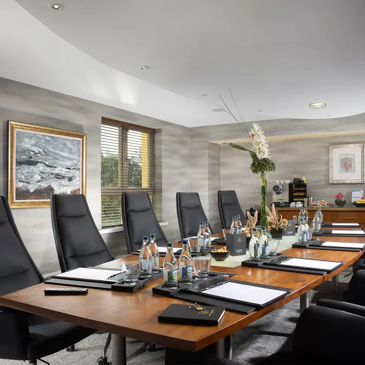 Contemporary boardroom at Castleknock Hotel, Dublin, perfect for executive meetings, strategic planning sessions, and corporate retreats. Featuring high-back chairs, a polished wooden table, and a fully serviced refreshment station. Organised by Dynamic Events Ireland.
