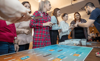 Corporate team engaged in a strategic collaboration game, analysing data on a digital tabletop during a team building workshop.
