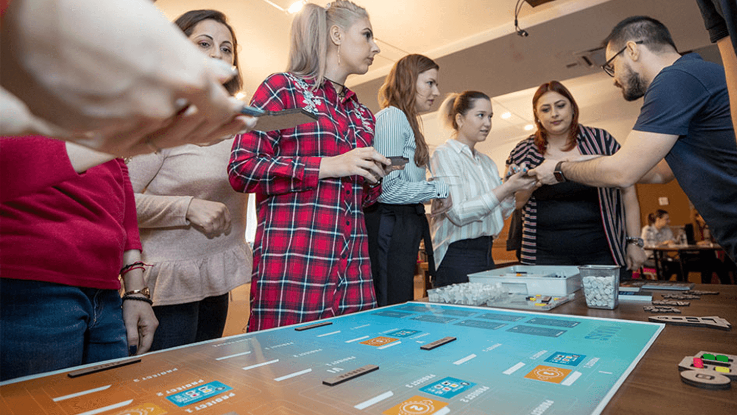 Corporate team engaged in a strategic collaboration game, analysing data on a digital tabletop during a team building workshop.