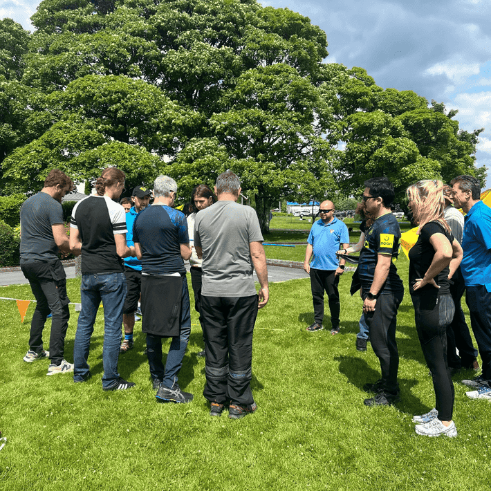 Wide shot of the outdoor event area showing multiple team activities in progress with teams participating around the space.