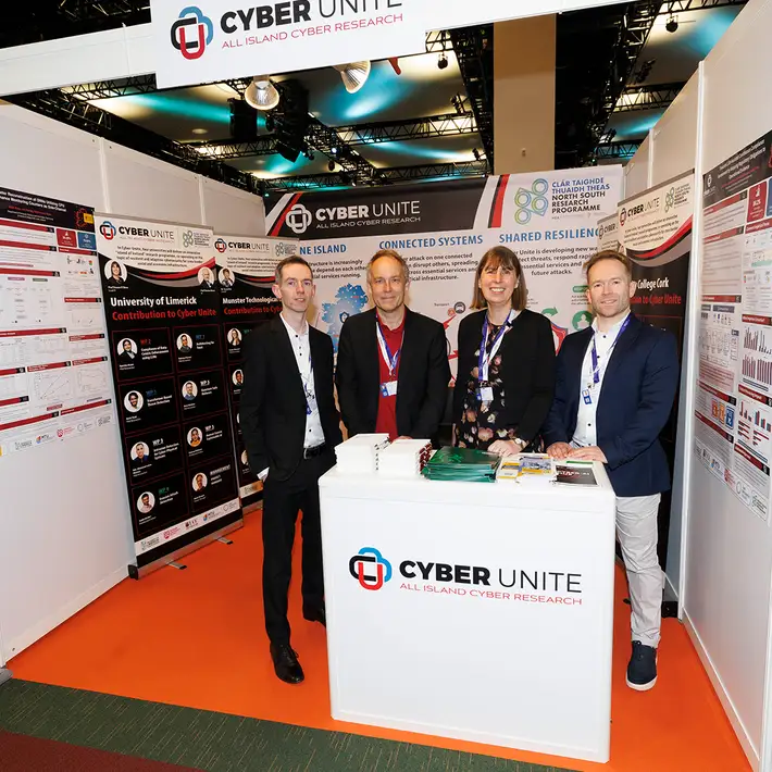 Four representatives at the Cyber Unite research exhibition stand, displaying cybersecurity research projects at the NCSC Cyber Expo.