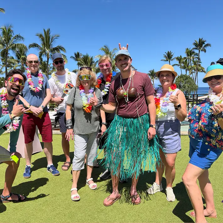 Corporate team building group in Hawaiian costumes during digital treasure hunt in Maui resort