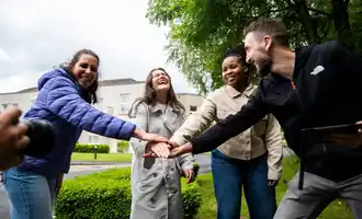 Onboarding team building activity with graduates collaborating outdoors on a sunny day.