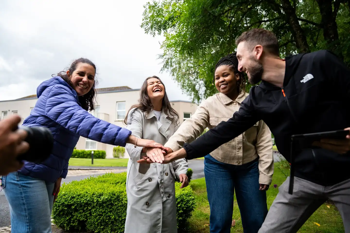Corporate team building activity in Ireland with colleagues smiling and joining hands outdoors during an August team event.