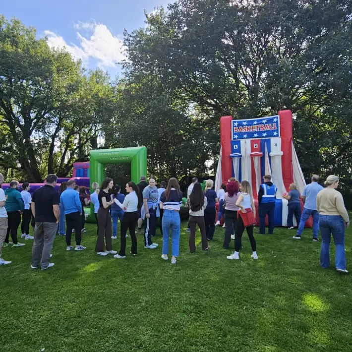 Resmed PEI colleagues gathered around inflatable basketball and team-building games during outdoor Team Olympics at The Johnstown Estate.