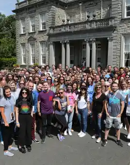 group of people standing in front of manor house