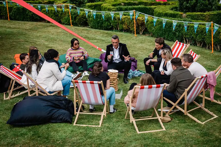 Team sitting on deckchairs listening to a magician entertaining during a relaxed corporate summer event
