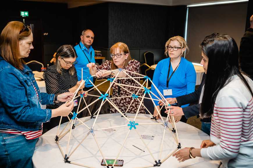 People collaborating to build domeworks structure during a team training activity.