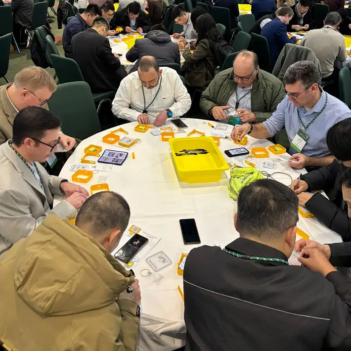Groups of Hexagon sales professionals work together assembling SolarBuddy lights at the Convention Centre Dublin, showcasing hands-on teamwork.