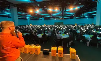 Corporate team in Ireland taking part in a SolarBuddy CSR team building event, holding assembled solar lights during the Hour of Power activity in a large conference venue.