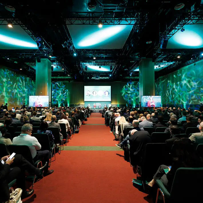 Wide view of delegates attending the NCSC Cyber Security Conference, showing the main stage, large screens and conference lighting.