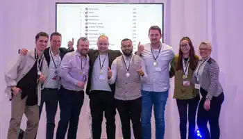 Corporate quiz winners posing with medals in front of live team scoreboard during team building event in Ireland