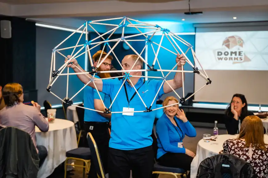 Dave holding up a completed Dome Works to a group of clients | Team Training