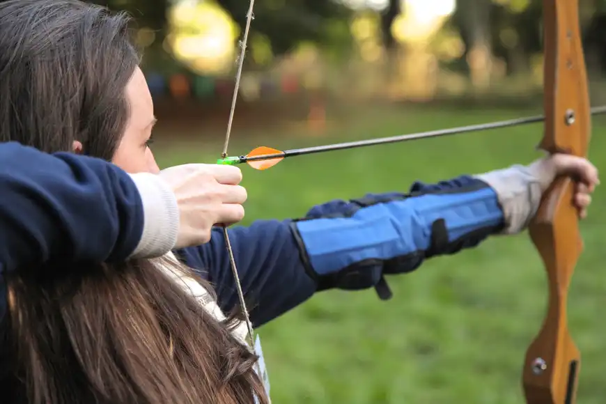 Employee aiming with a bow during an outdoor archery team building activity in Ireland.