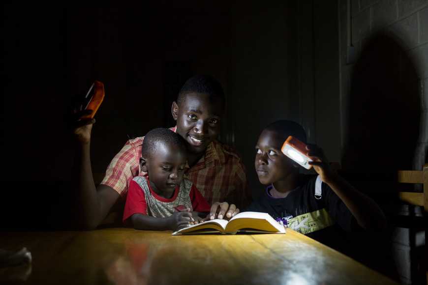 African family reading at night using donated solar lights from SolarBuddy CSR initiative