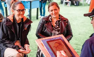 corporate team building caricature activity with two colleagues laughing while live caricature artist draws them at outdoor company event in Ireland